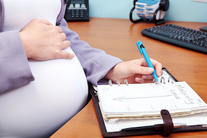 Photo,Of,A,Pregnant,Woman,In,An,Office,Writing,The